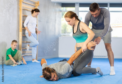 During self-defense training, man coach helps teen girl student complete exercise, neutralize enemy, correctly perform action and defensive movement photo