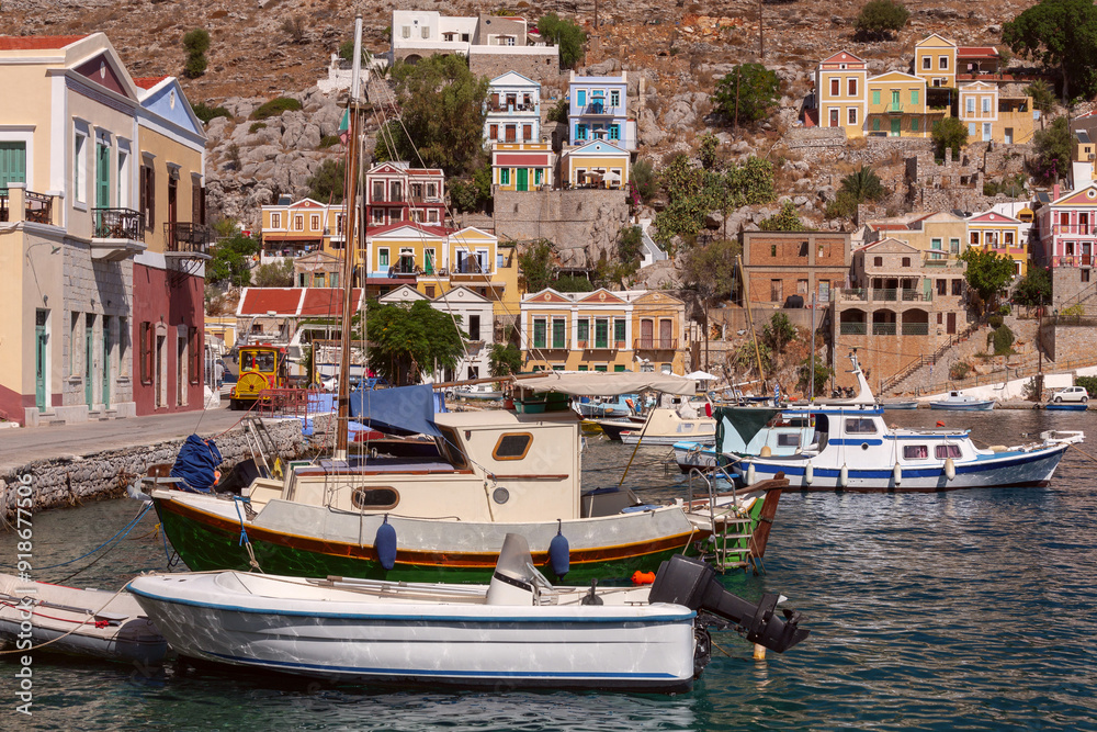 Colourful house facades and fishing boats in the bay of Symi village at sunset. Colourful house facades and fishing boats in the bay of Symi village at sunset.