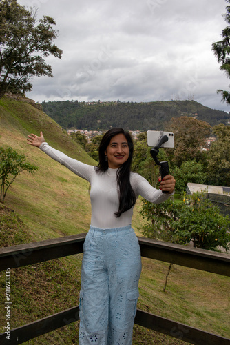 Latina woman visiting the city of Cuenca with the Pumapungo ruins in the background, using her phone to record herself while exploring the area