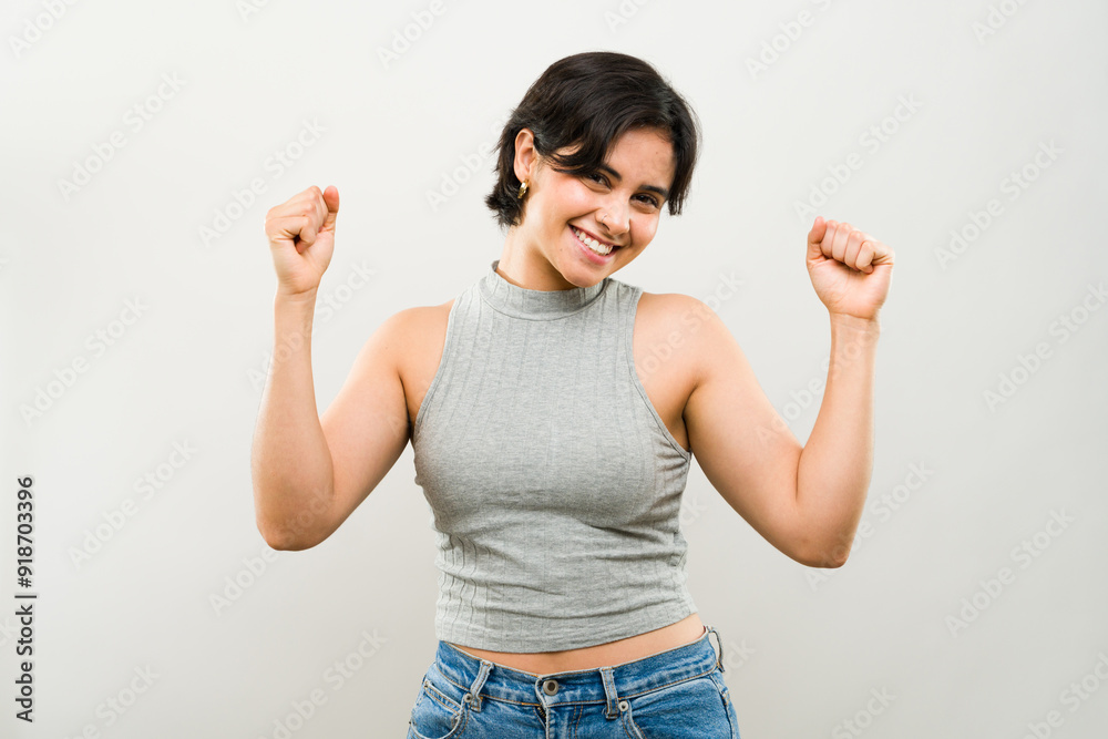 Portrait of a joyful young woman triumphantly raising her fists in the air to celebrate a victory or success Portrait of a joyful young woman triumphantly raising her fists in the air to celebrate a victory or success