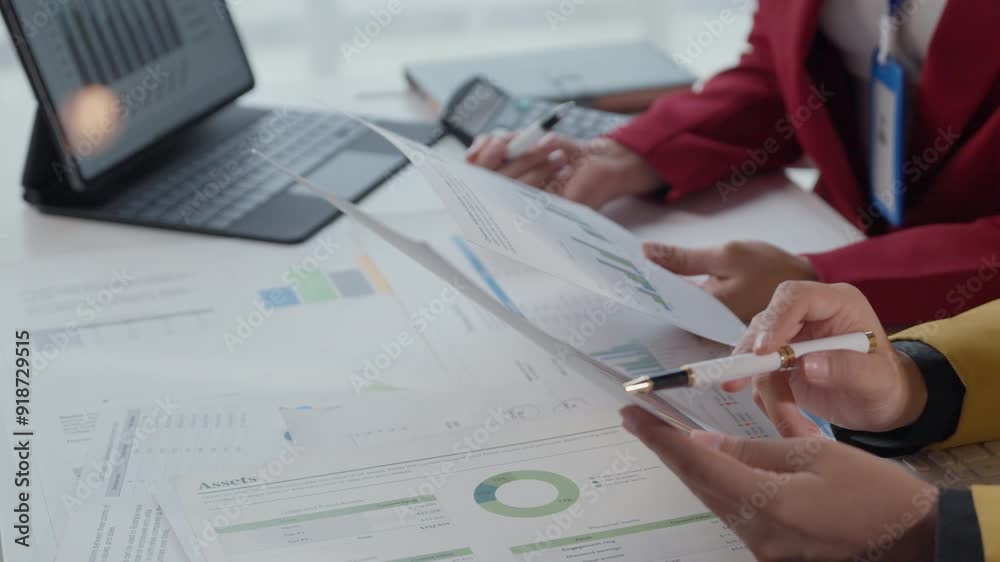 Business team collaborating and analyzing financial documents and data reports. Close up of hands discussing charts and graphs over a tablet. Office desk workspace