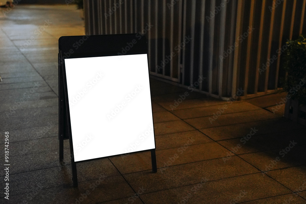 Blank white outdoor advertising stand or sandwich board mock up template. Clear street signage board placed by an outdoor dinning area of a restaurant. Background texture of standee on street.