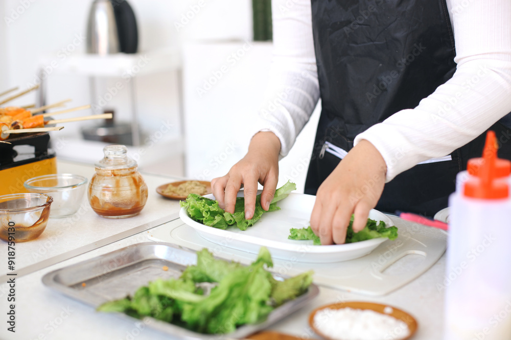 Woman making salad, put the lettuce leaves into a plate at the kitchen Woman making salad, put the lettuce leaves into a plate at the kitchen