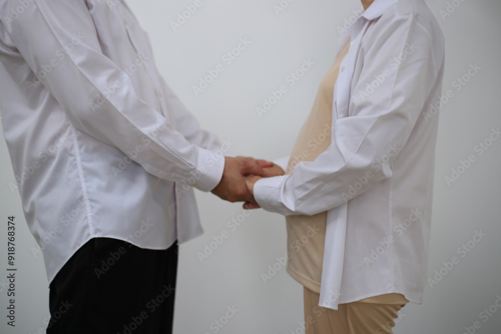 A young man hugs his pregnant wife while standing in a room in his house. A young man hugs his pregnant wife while standing in a room in his house.