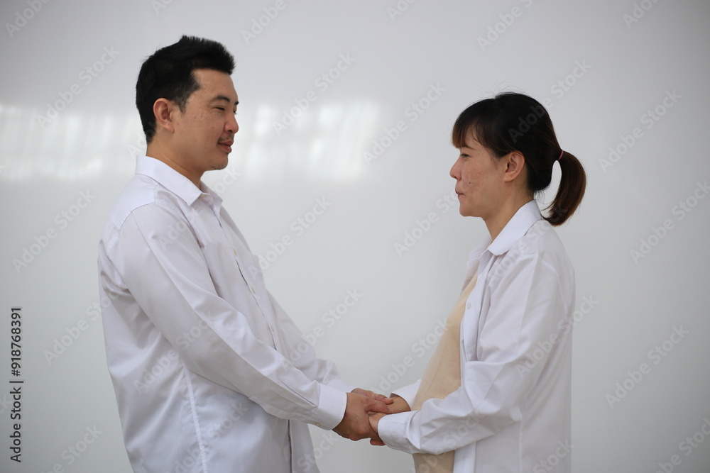A young man hugs his pregnant wife while standing in a room in his house. A young man hugs his pregnant wife while standing in a room in his house.