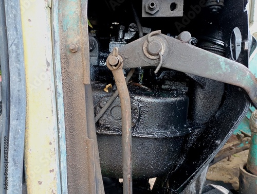 A fragment of the engine compartment of an old agricultural tractor contaminated with black manufactured engine oil.