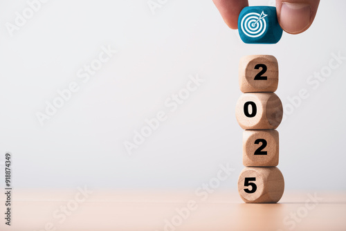 Hand putting blue dartboard with arrow on the top of 2025 year for setup business objective target and goal in new year concept. photo