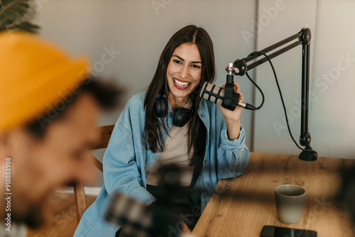 People in the podcast studio talking and recording, focus on a woman talking into a mic photo