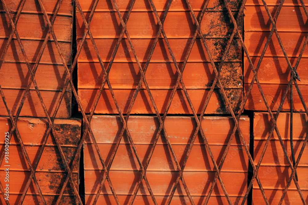 Pile of clay construction blocks behind worn rusty fence Pile of clay construction blocks behind worn rusty fence