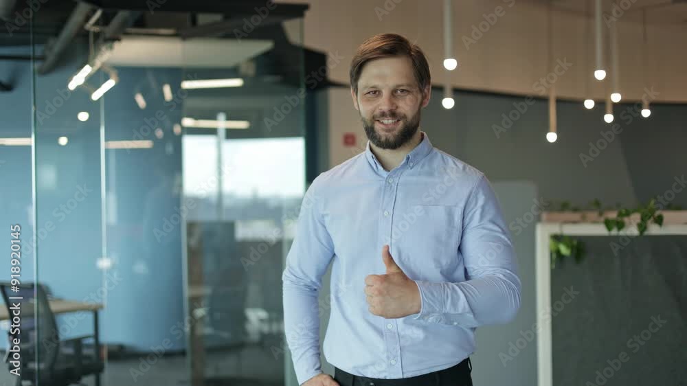Happy businessman in his modern office gives a thumbs up with confidence. Great for business and corporate themes. Happy businessman in his modern office gives a thumbs up with confidence. Great for business and corporate themes.