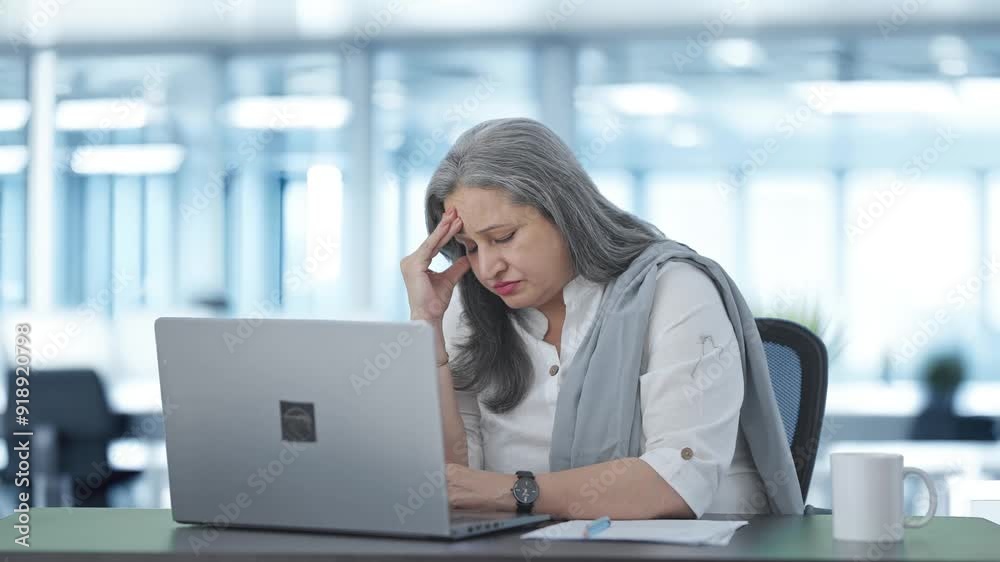 Tensed Indian senior female manager working on laptop