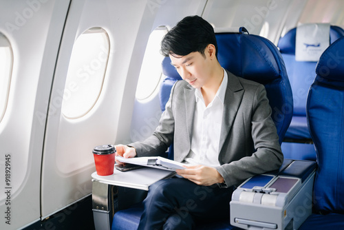 Young Asian executive excels in first class, multitasking with digital tablet, laptop and smartphone.