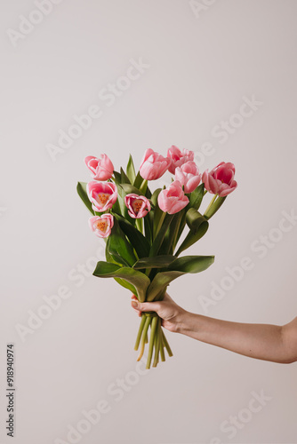 Female hand holding pink tulip flowers bouquet