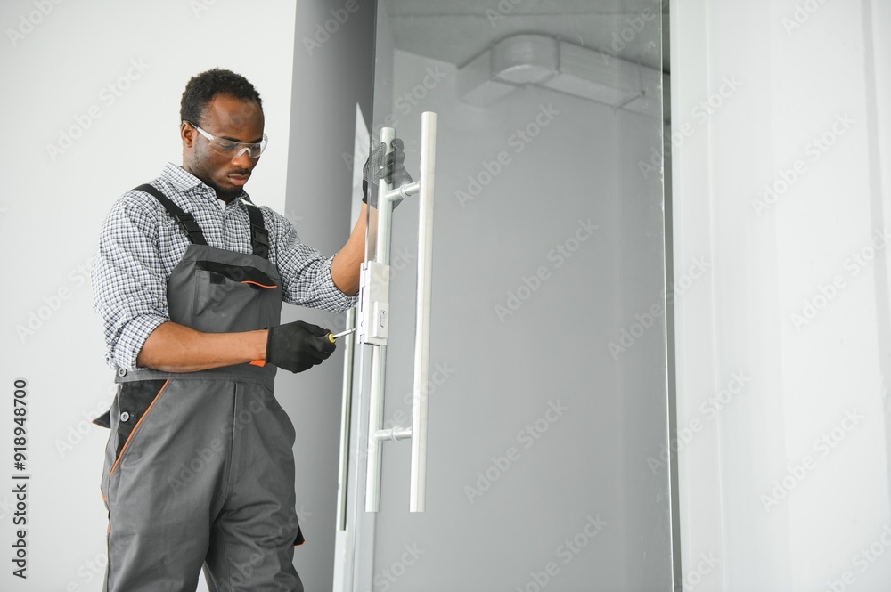 Worker installing glass door at office Worker installing glass door at office