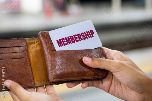 close up of a woman's hand holding a membership card in a brown wallet. paying with a membership card.