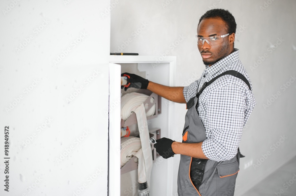 The worker installs or inspects Fire extinguisher and fire hose reel in building corridor The worker installs or inspects Fire extinguisher and fire hose reel in building corridor