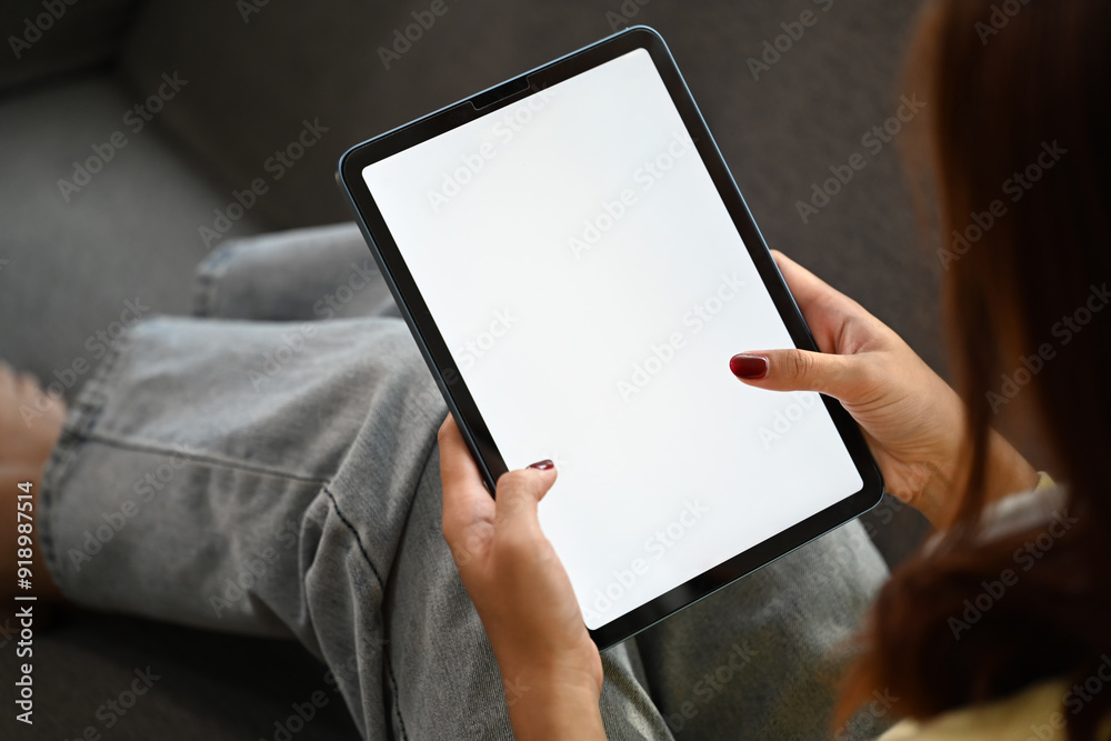 Young woman sitting in cozy sofa holding digital tablet with white blank screen Young woman sitting in cozy sofa holding digital tablet with white blank screen