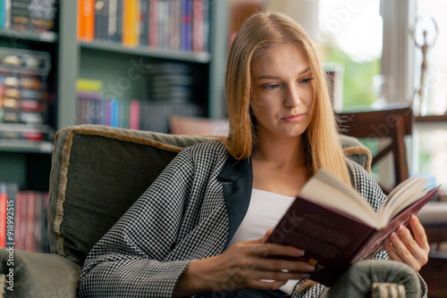 close up in a beautiful bookstore a young girl with long hair sitting in a chair reads a book passive rest student years photo