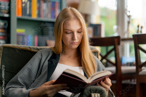 close up in a beautiful bookstore a young girl with long hair sitting in a chair reads a book passive rest student years photo