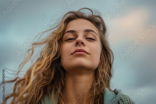 A woman with long blonde hair is smiling and looking up at the sky