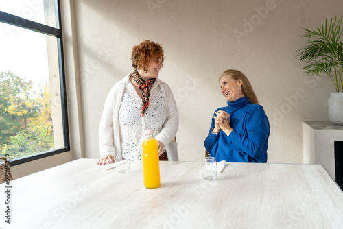 Adult female friends chatting happily in a minimalist space