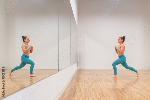 Woman practicing Anjaneyasana yoga pose with reflection photo