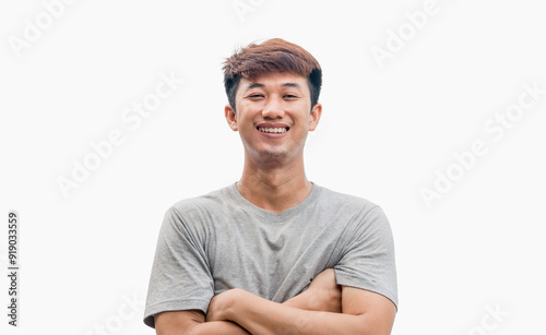 A young Asian man in his 20s wearing a gray t-shirt stands confidently with his arms crossed over his chest, isolated on a gray background. Positive person.