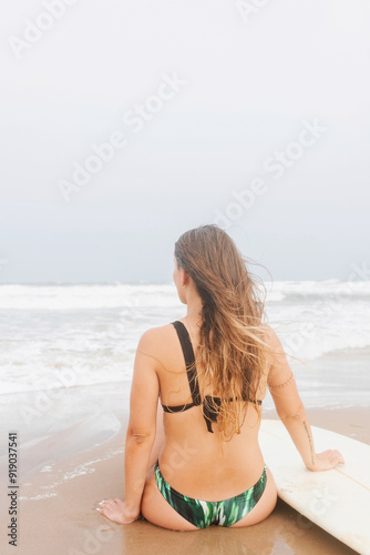 Unrecognizable surfer in swimwear with surfboard resting on sea beach