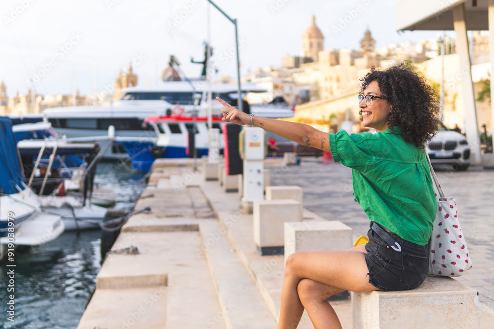 Smiling woman sitting on bench and pointing near marina Smiling woman sitting on bench and pointing near marina