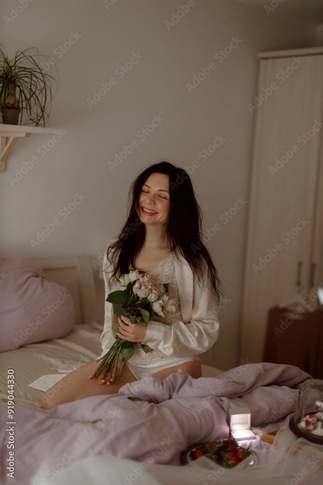 Happy woman holding bouquet of flowers with engagement ring on bed Happy woman holding bouquet of flowers with engagement ring on bed