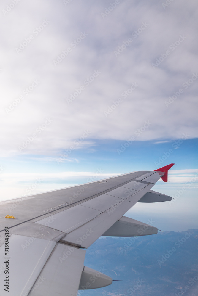 Airplane flying under cloudy sky over ocean and land Airplane flying under cloudy sky over ocean and land