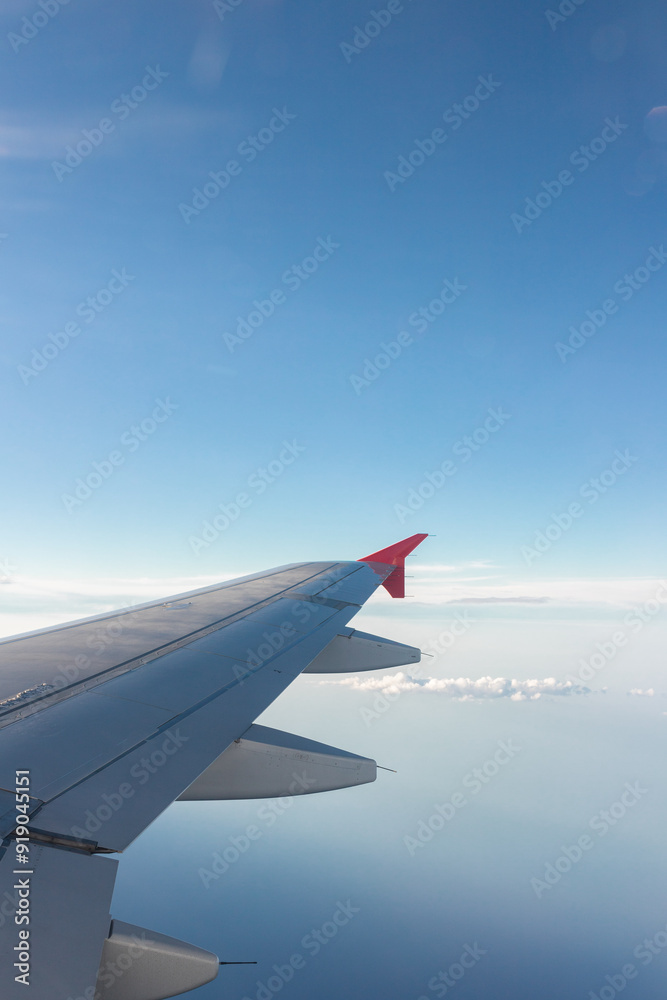 Airplane flying under cloudy sky over ocean and land Airplane flying under cloudy sky over ocean and land