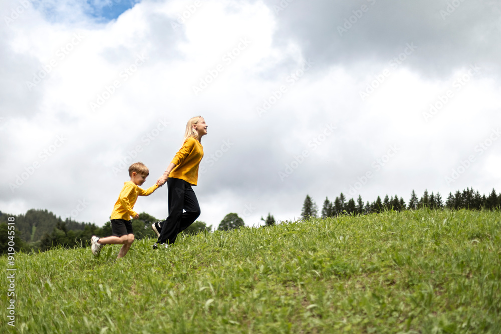 Brother and sister holding hands and running uphill Brother and sister holding hands and running uphill