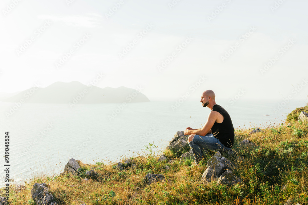 Young man sitting on mountain and looking at view Young man sitting on mountain and looking at view