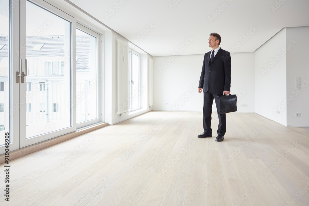 Real estate agent standing and carrying briefcase in hand at empty apartment Real estate agent standing and carrying briefcase in hand at empty apartment