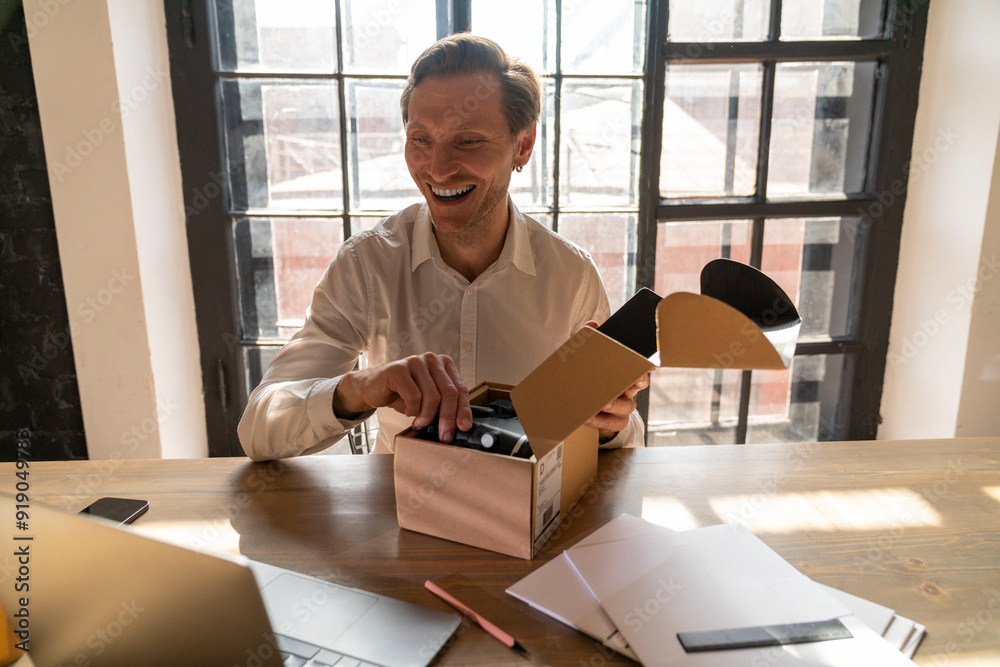 Happy businessman unboxing package at desk Happy businessman unboxing package at desk