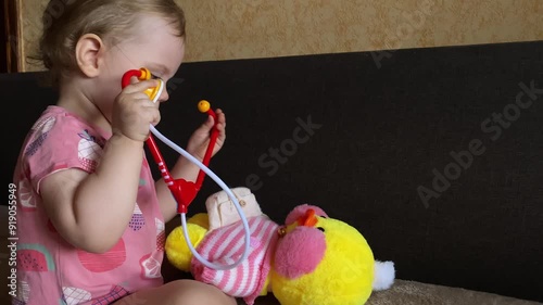 A child plays with a yellow duck. A child plays doctor.