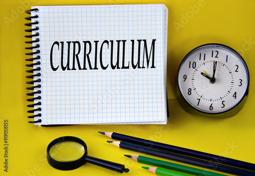 CURRICULUM - words in a white notebook with an alarm clock, pencils and magnifying glass in the background