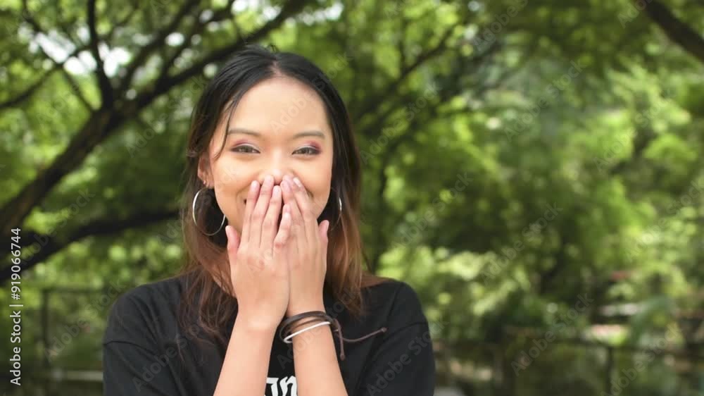 A young asian goth girl looks amazed and thrilled, mouth agape at exciting news. Pleased and ecstatic. Outdoor park scene. Slowed down 50 percent. A young asian goth girl looks amazed and thrilled, mouth agape at exciting news. Pleased and ecstatic. Outdoor park scene. Slowed down 50 percent.