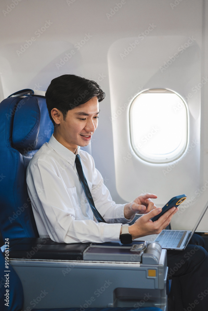 Traveling and technology. happy young businessman working on laptop computer and smartphone while sitting in airplane. Traveling and technology. happy young businessman working on laptop computer and smartphone while sitting in airplane.