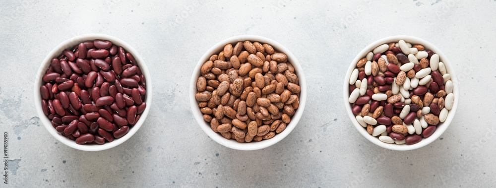 Ceramic bowls with red and variegated and mixed raw dry beans on kitchen table.Macro. Ceramic bowls with red and variegated and mixed raw dry beans on kitchen table.Macro.