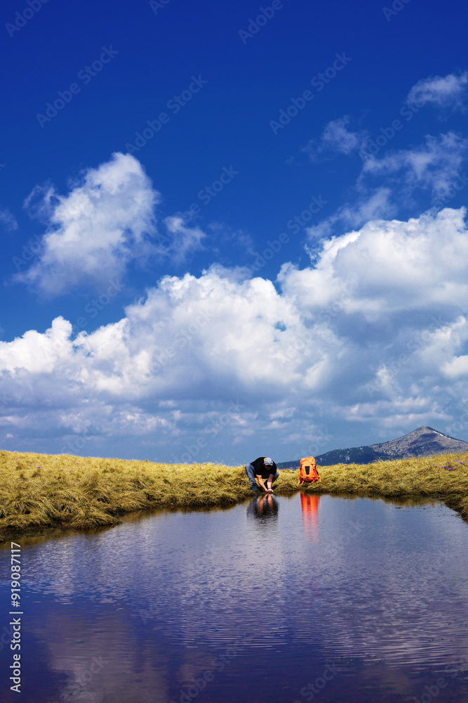 Mountaineer trekking on the beautiful mountain and mountain lake with camera making photo.