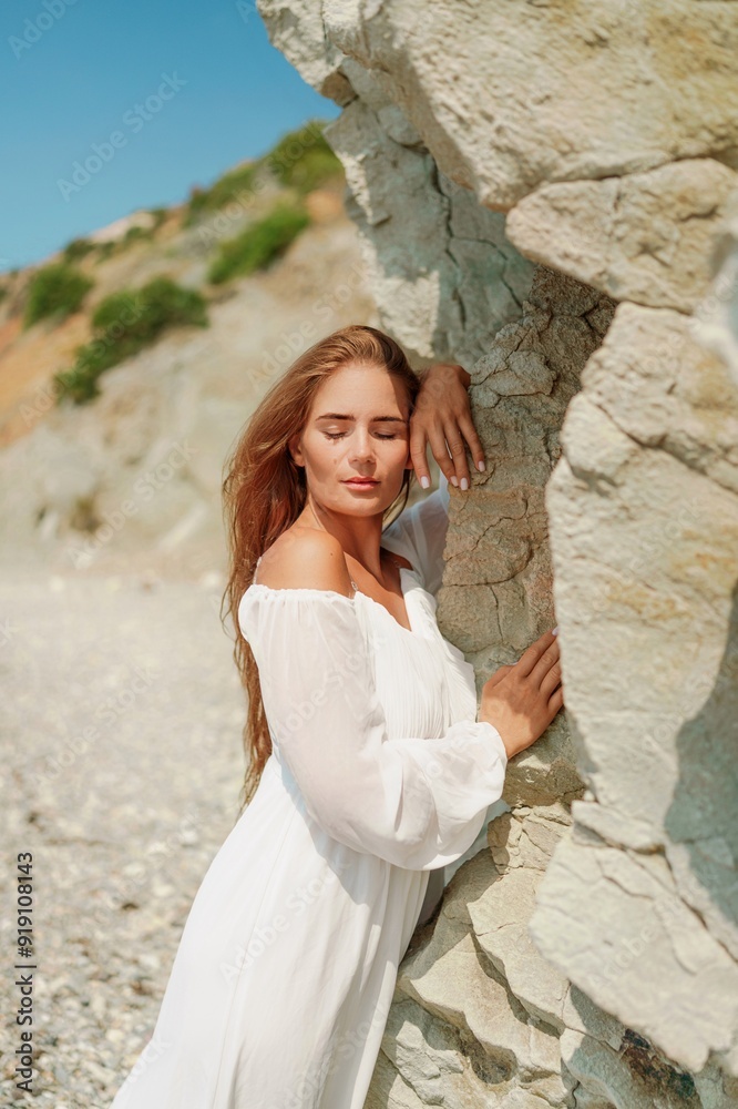 A woman in a white dress is standing on a rocky beach. Concept of serenity and tranquility, as the woman is enjoying the natural beauty of the beach. A woman in a white dress is standing on a rocky beach. Concept of serenity and tranquility, as the woman is enjoying the natural beauty of the beach.