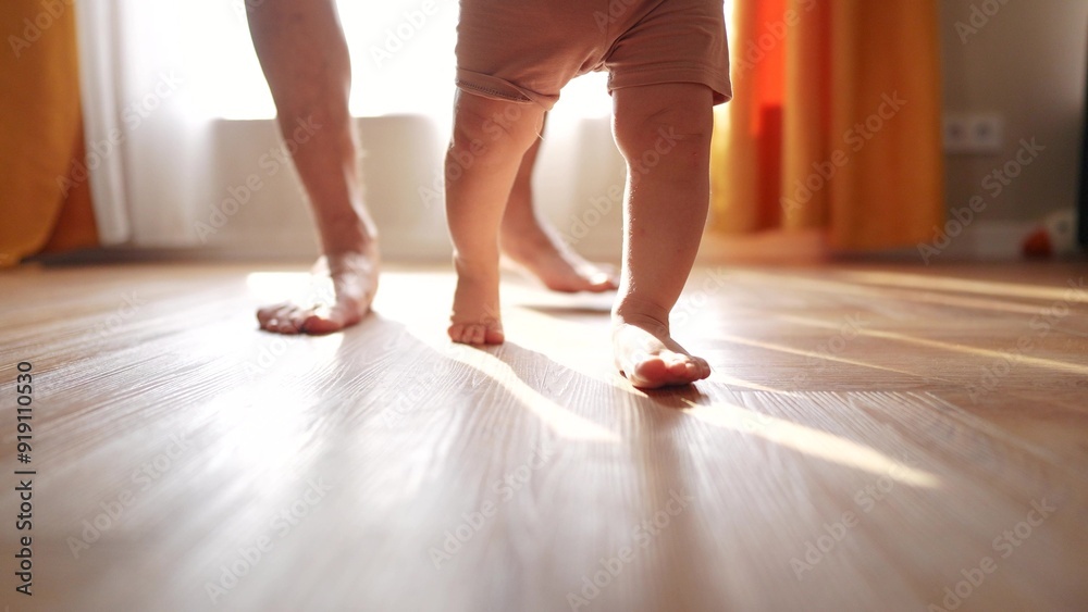 Daddy and baby taking the first steps. Child-father concept. A baby is taking the first steps on its legs. Dad teaches baby to help the little one take life his first steps in. Daddy and baby taking the first steps. Child-father concept. A baby is taking the first steps on its legs. Dad teaches baby to help the little one take life his first steps in.
