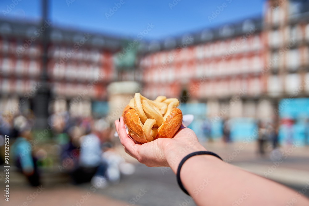 Fototapeta premium unrecognizable person holding a calamari sandwich in his hand, traditional Madrid food in the Plaza Mayor