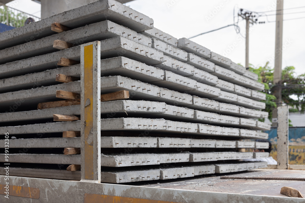 A stack of gray concrete sheets with wooden boards on truck.