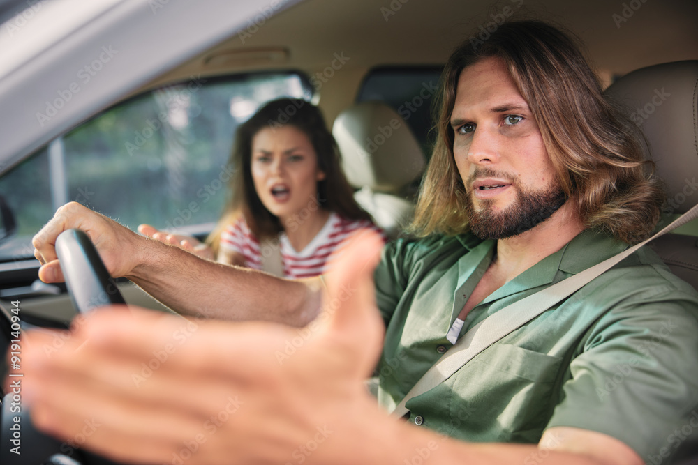 A couple in a car, the man is driving with an upset expression, while the woman in the passenger seat looks frustrated and is gesturing expressively A couple in a car, the man is driving with an upset expression, while the woman in the passenger seat looks frustrated and is gesturing expressively
