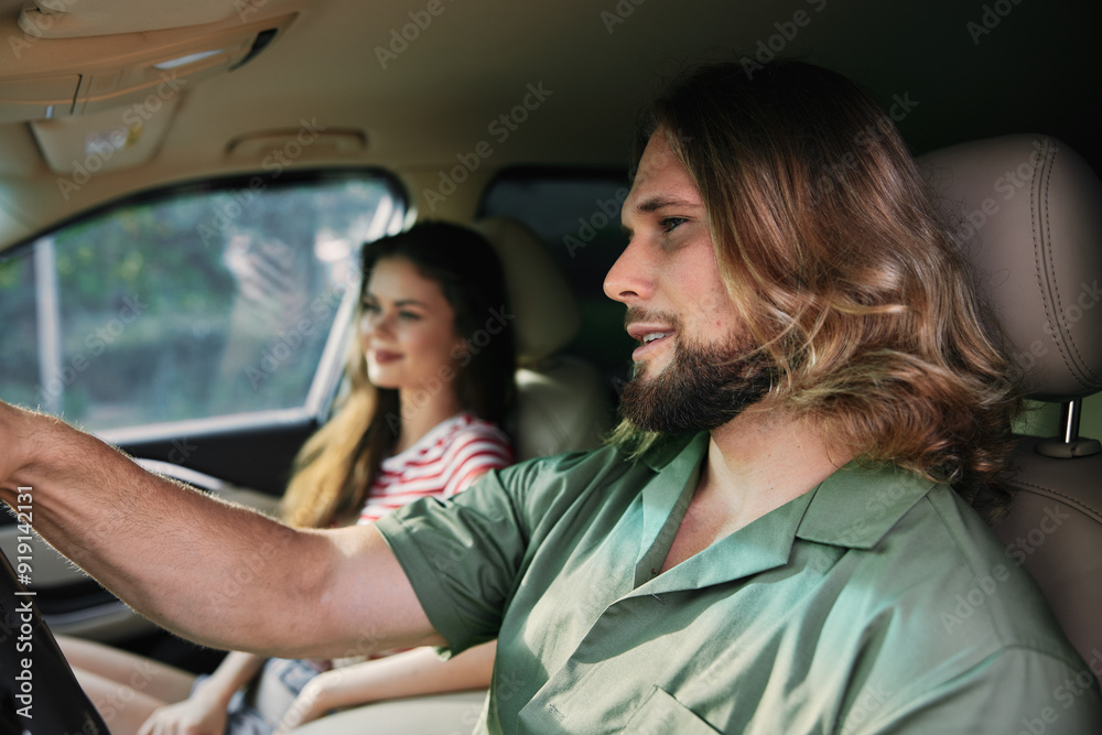 A man and a woman sitting in a car, facing forward, with the man driving and the woman relaxed Soft natural light illuminates the scene A man and a woman sitting in a car, facing forward, with the man driving and the woman relaxed Soft natural light illuminates the scene