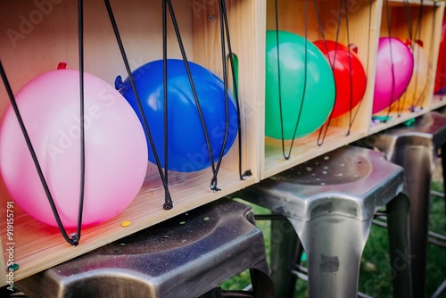 Jeu de fête foraine avec ballons colorés à éclater à la fléchette, alignés dans une structure en bois.