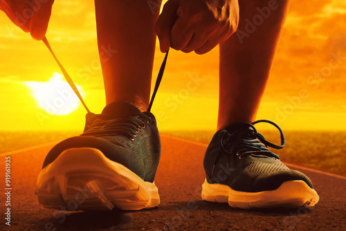 Closeup silhouette of young man tying running shoe lace on the street in the morning